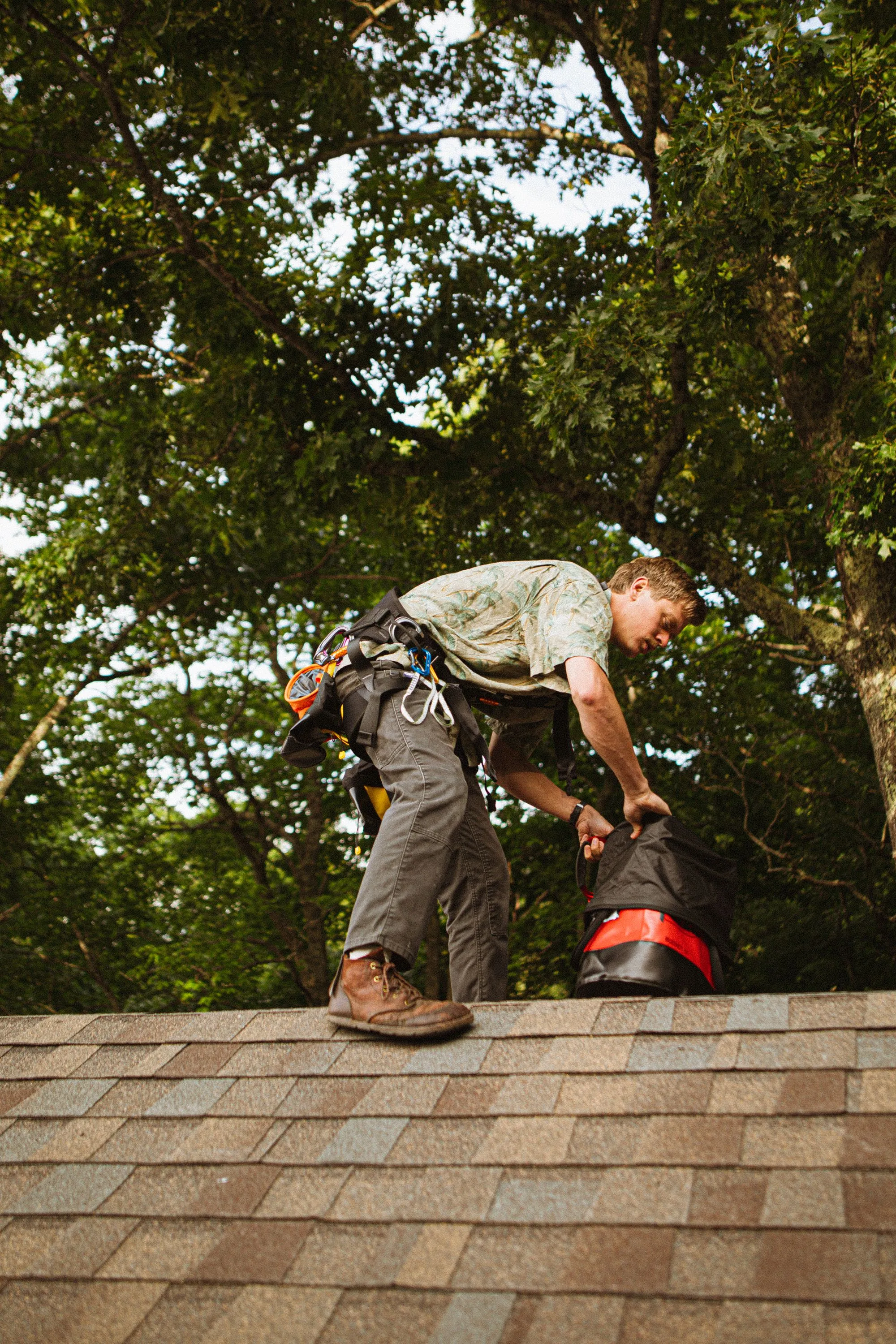 A roofer moving across a residential roof slope in safety gear
