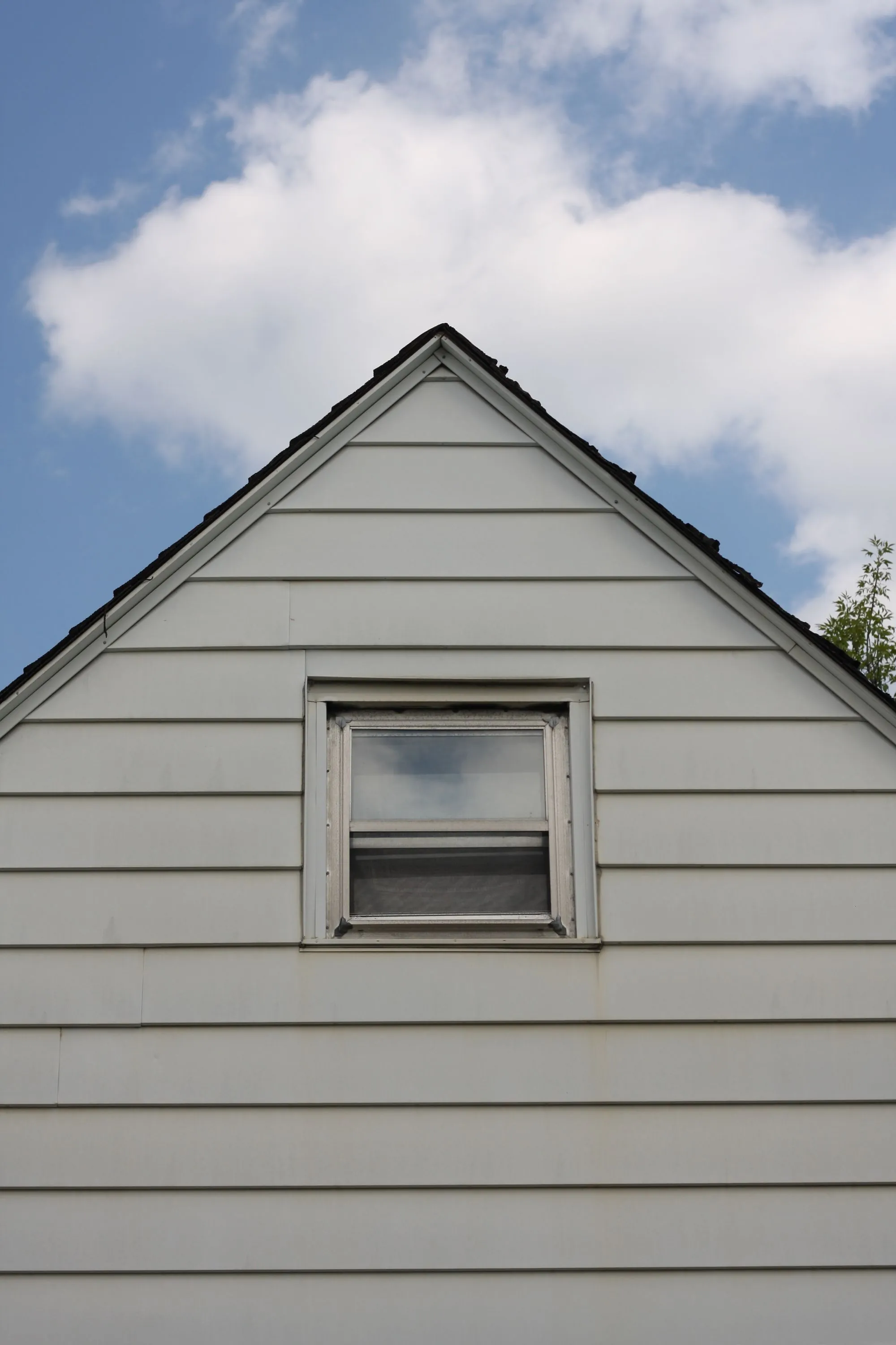 The gable end of a sided house meeting a clear sky